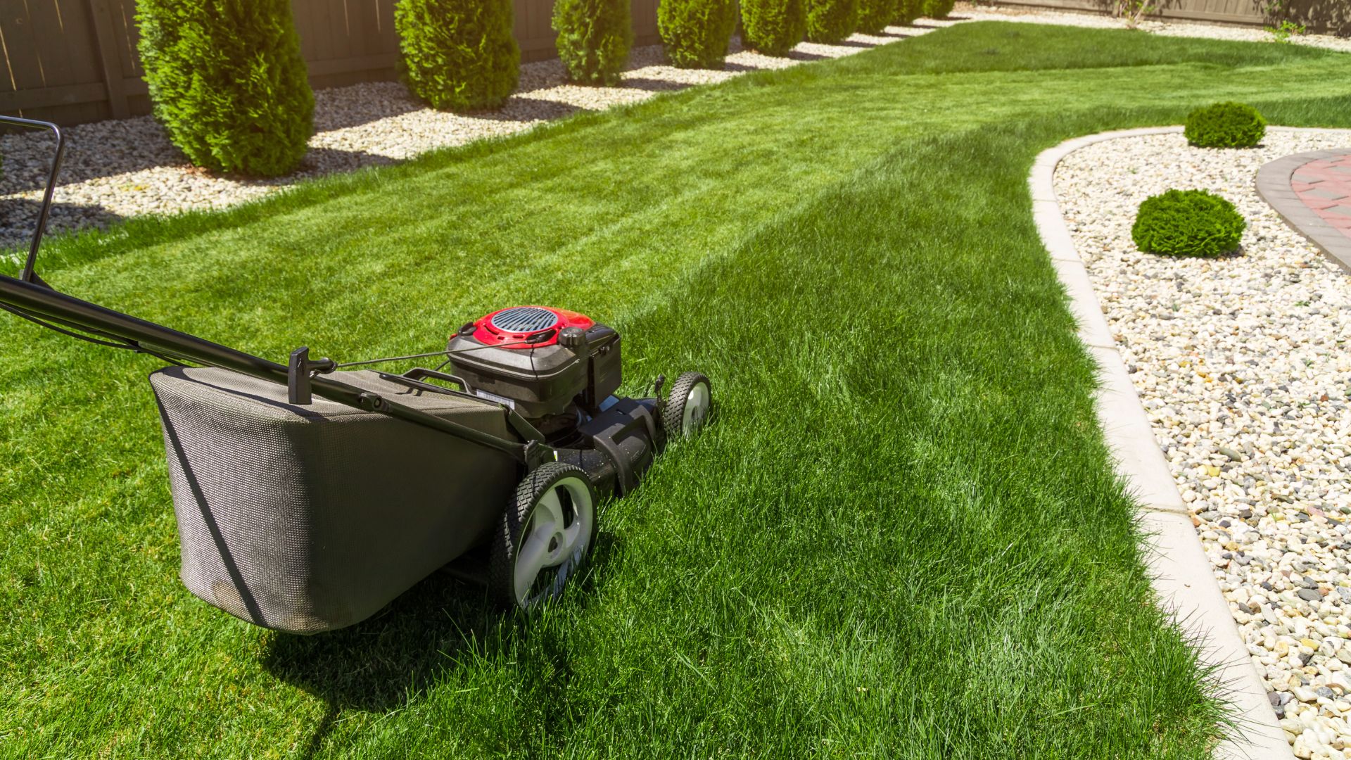Lawn mower on freshly cut grass with landscaped garden in background