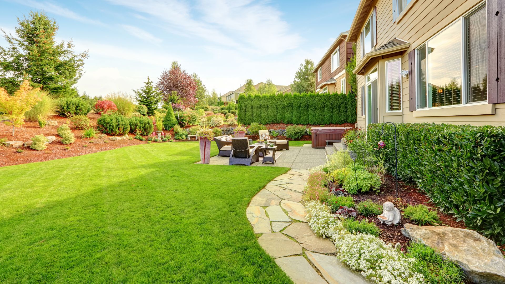 Beautifully landscaped backyard with green lawn, patio, and flowering plants